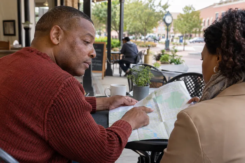 A visitor consulting a folded street map on a pedestrian square with a companion