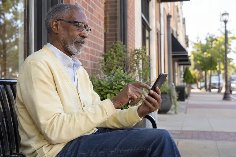 A visitor checking an address on a phone outside an unbranded mixed-use brick building