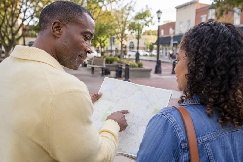 A visitor consulting a folded street map on a pedestrian square with a companion