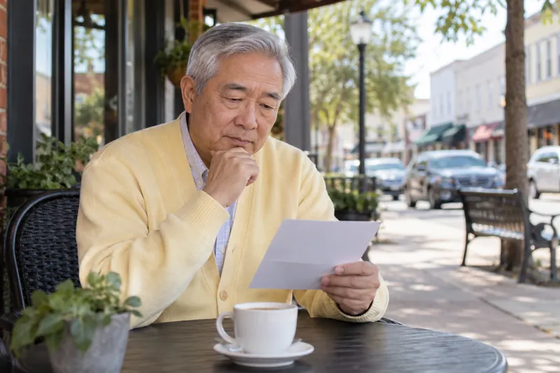 A visitor reading an appointment reminder by a cafe window overlooking an ordinary main street