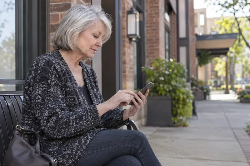 A visitor checking an address on a phone outside an unbranded mixed-use brick building