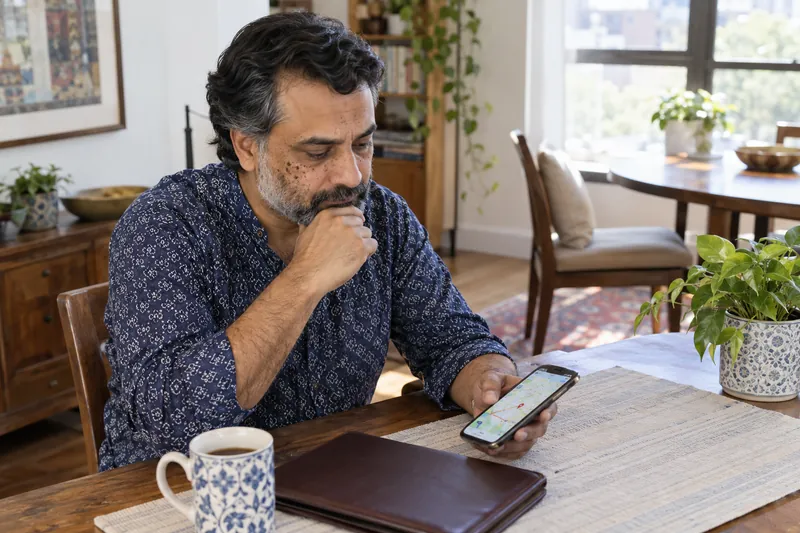 A visitor sitting at a public-library table with a phone map and a closed document folder