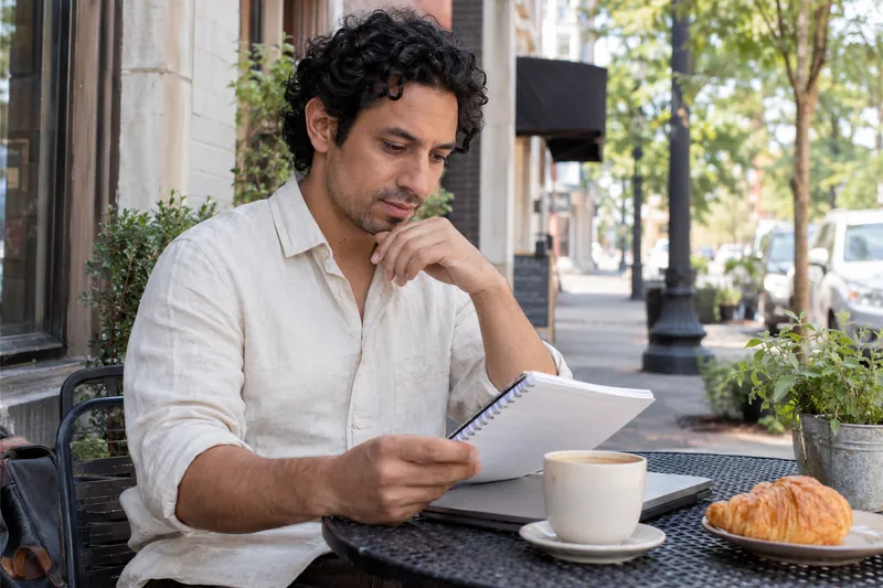A visitor reviewing an appointment note at an outdoor cafe table before a local office visit