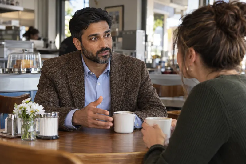 A visitor discussing a local errand over coffee in a modest neighborhood diner