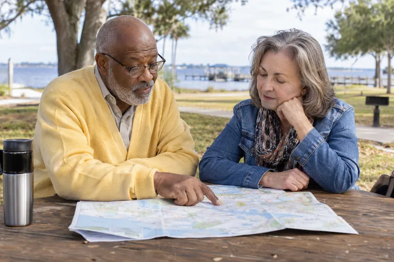 A visitor reviewing a map with a friend at a picnic table in a small public park