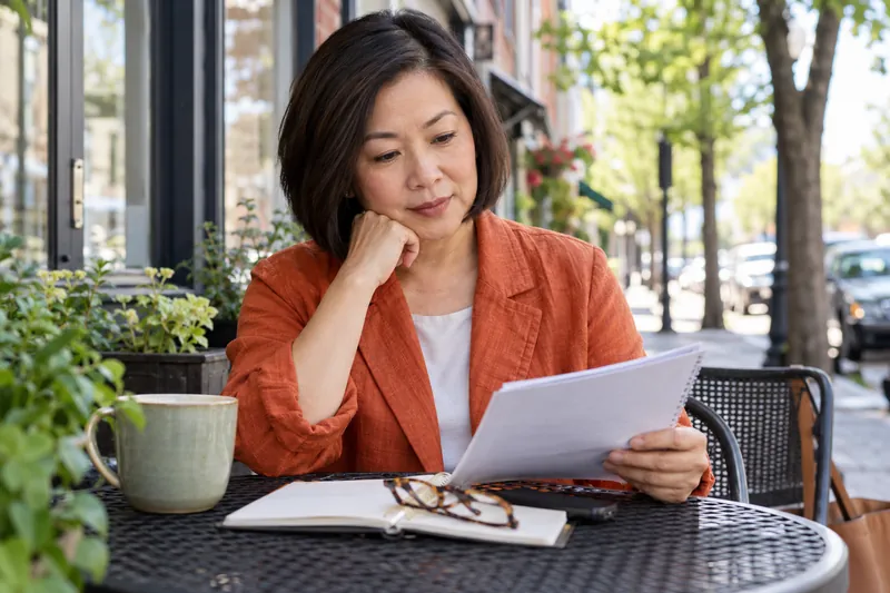 A visitor reviewing an appointment note at an outdoor cafe table before a local office visit